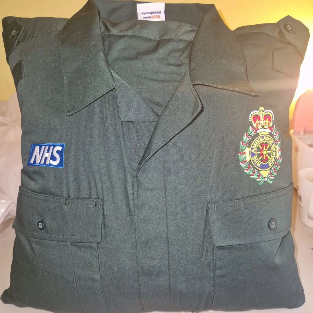 Memory cushion made from an NHS ambulance service shirt, showing the collar, pockets and embroidered badge