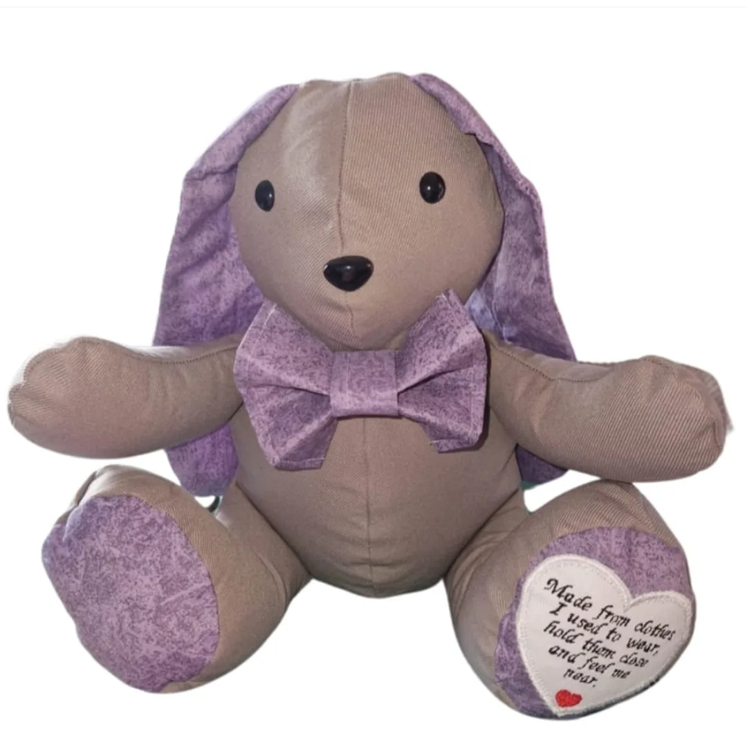 Memory bunny made from soft beige fabric with lilac ears, paw pads and dicky bow, with an embroidered heart poem